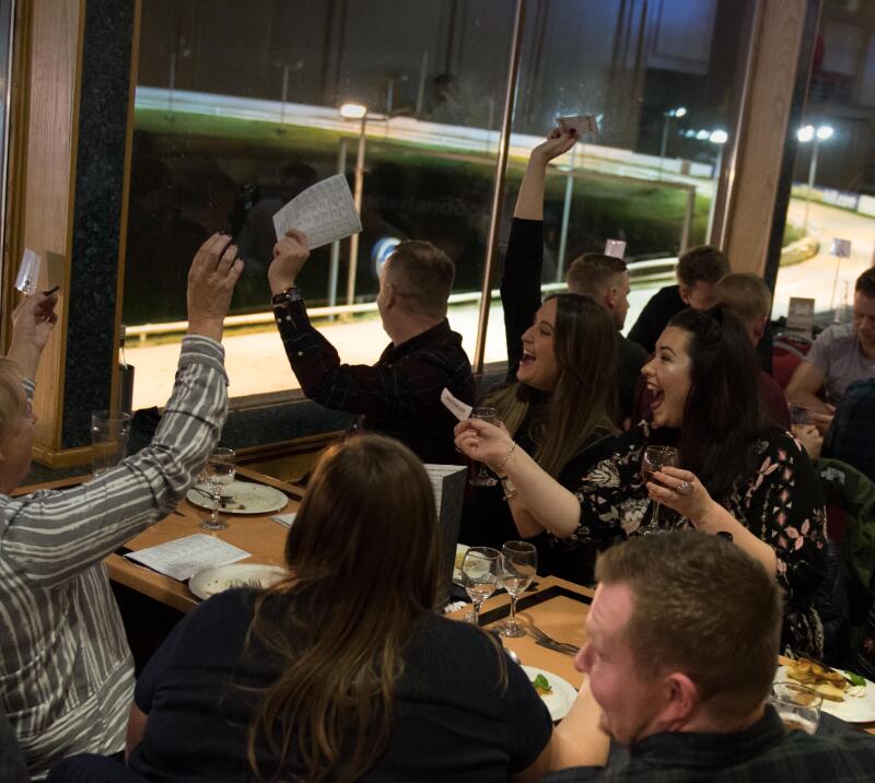 A group of hospitality guests at Sunderland greyhounds cheers the race